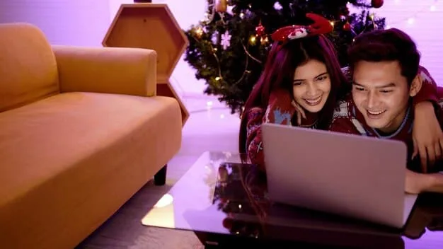 A family smiling and pointing at a laptop screen displaying a travel booking website with discounted prices. Warm, inviting lighting with a modern home interior in the background.