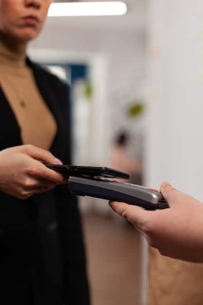 A close-up shot of a store credit card being swiped at a checkout terminal in a clothing store. The focus is on the card and the point-of-sale system.
