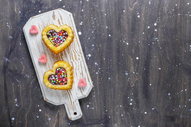 An overhead shot of a batch of shortbread cookies arranged on a wooden cutting board, some decorated with icing and sprinkles.