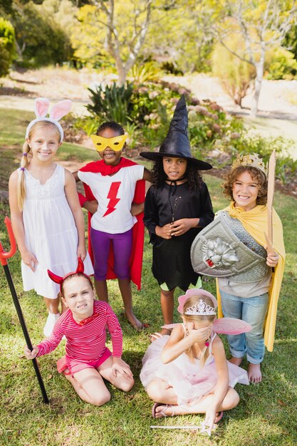 A group of children laughing and engaging in imaginative play with a set of dress-up clothes and accessories. Focus on the diversity of the costumes and the children's expressions of joy.